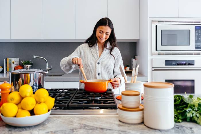 woman smiling wearing sweater and cooking in the kitchen